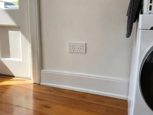 Double power point on a white wall above a timber floor in a home laundry in Ryde